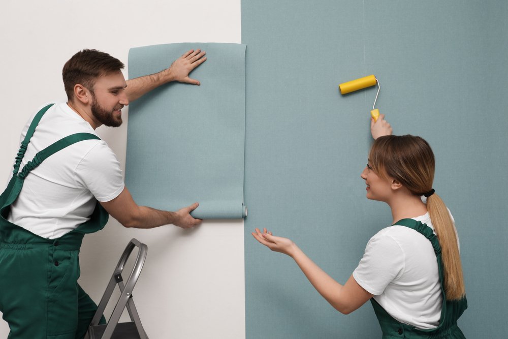 Een Renovlies specialist in actie, nauwkeurig Renovlies behang van 200 gram per vierkante meter aanbrengend op een muur voor een perfecte afwerking.