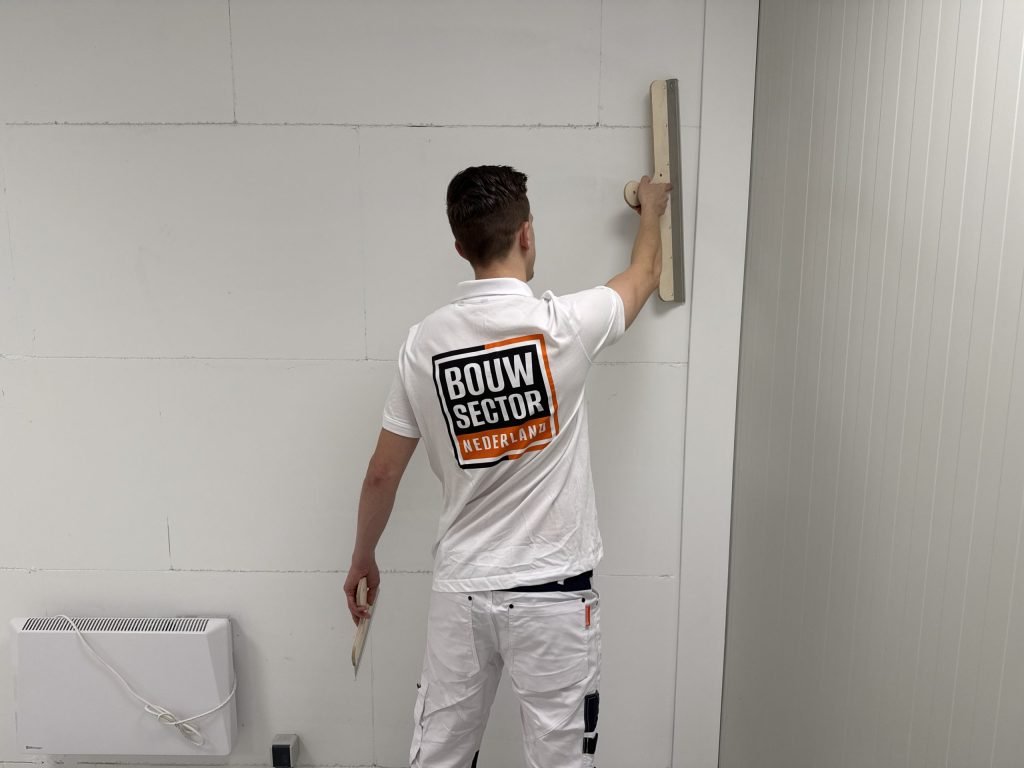 Stukadoor van Bouwsector Nederland trekt een wand vlak met een spaan